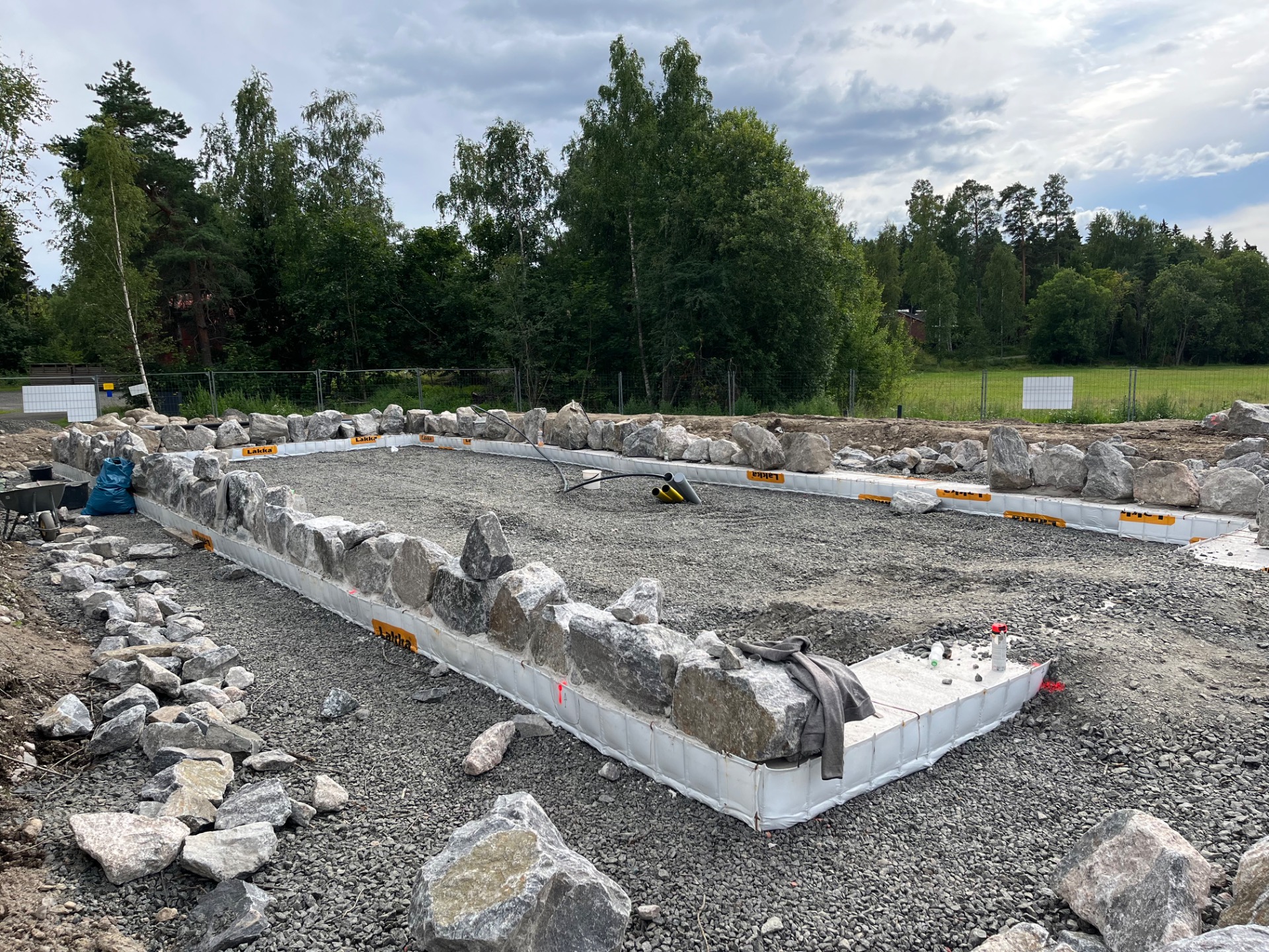 19.7.2026 Anturan päälle ladotaan kylmäladontana luonnonkivisokkeli. Työ on tässä alkanut. Latominen ja muuraaminen kestää noin kaksi viikkoa.